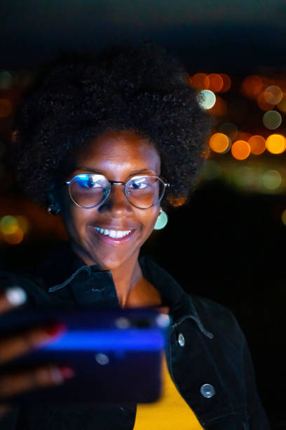 Woman taking a selfie with city lights at background stock photo