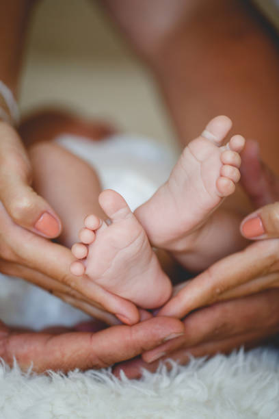 istock Tiny newborn's foot in the mother hands in soft focus 1163500425