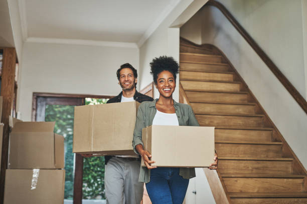 Cropped shot of an affectionate young couple smiling while carrying boxes into their new home