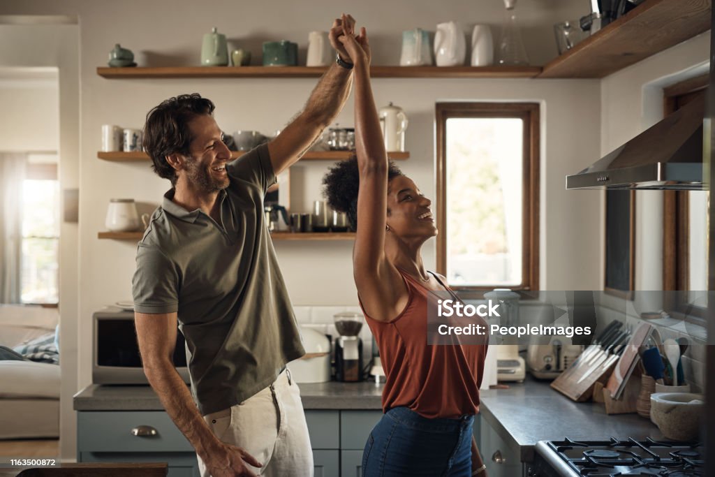 He loves dancing with his queen Cropped shot of an affectionate young couple dancing together in their kitchen at home Dancing Stock Photo
