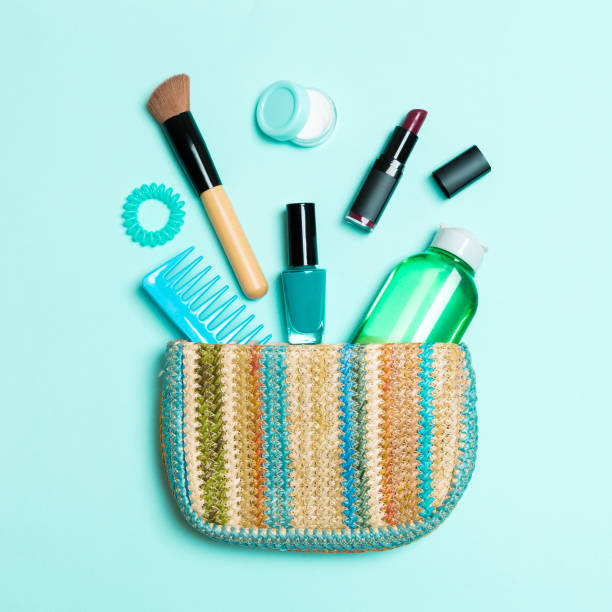 make up products spilling out of cosmetics bag on blue pastel background with empty space for your design - pampering nail polish make up spilling imagens e fotografias de stock