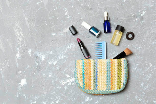 make up products spilling out of cosmetics bag on grey cement background with empty space for your design - pampering nail polish make up spilling imagens e fotografias de stock