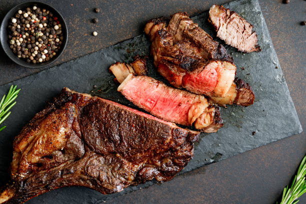 Top view of dry-aged marble beef steak Tomahawk on black slate with spices. Flat lay, dinner concept. Top view of dry-aged marble beef steak Tomahawk on black slate with spices. Flat lay, dinner concept. wagyu beef stock pictures, royalty-free photos & images