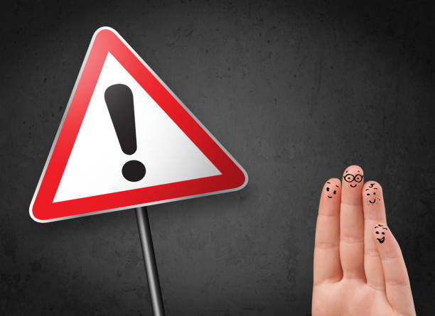 istock Happy smiley fingers looking at triangle warning sign with exclamation mark 1163505432