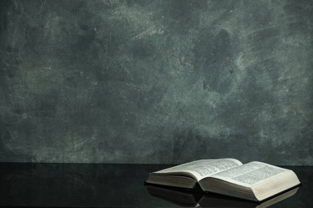 istock Bible on a black glass table. Beautiful gray wall background 1163506379