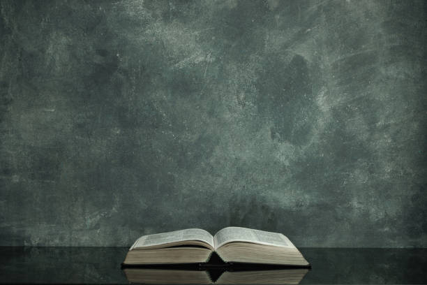 istock Bible on a black glass table. Beautiful gray wall background 1163507400