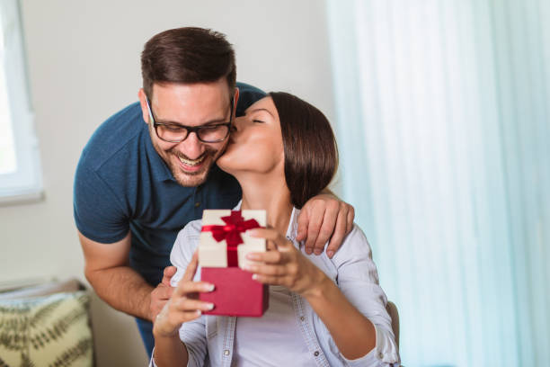 istock Smiling man surprises his girlfriend with present at home 1163513757