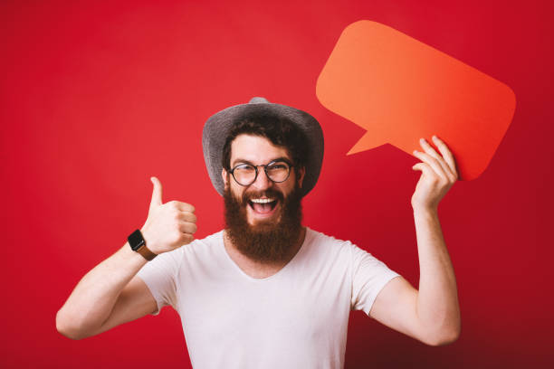 istock Handsome bearded guy,  cheerfully, showing thumb up while holding a empty blank, over isolated background 1163516581
