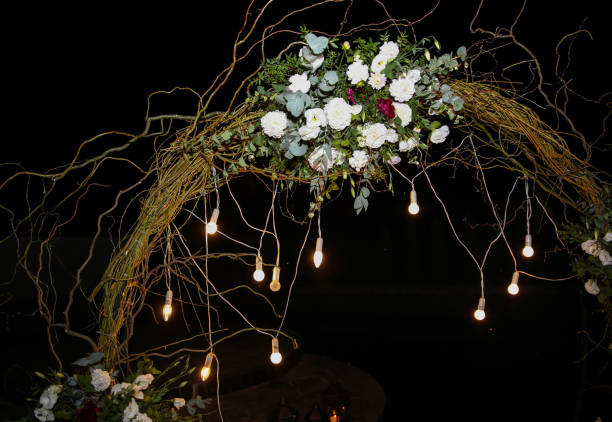 istock White flowers arch at the wedding ceremony. Outdoors decoration. Romantic rustic style. Lamps lights in the evening. 1163517493