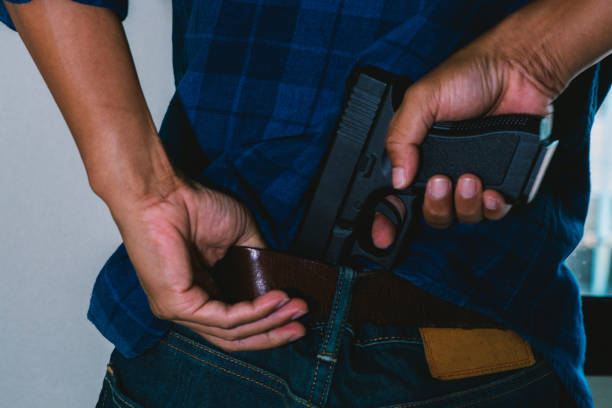 istock Man hiding gun in back pants, close-up image 1163520911