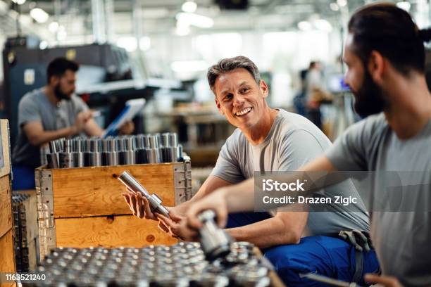 Gelukkige Handarbeiders Praten Terwijl Ze Samenwerken Bij Steel Factory Stockfoto en meer beelden van Geluk