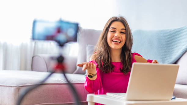 istock Woman sitting beside desk with laptop while filming her broadcast 1163522093