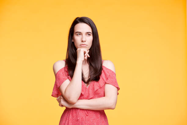 istock Young pensive or discontent woman keeping one hand by chin 1163522754