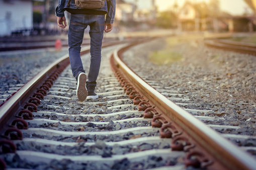 Man walk away on railroad with warm light.Selective focus.Traveler man on railroad.