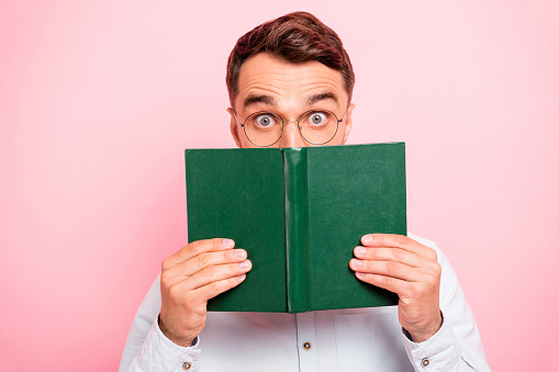 Close up photo portrait of comic cheerful enthusiastic with big staring looking, eyes holding paper green book and looking at you isolated pastel background