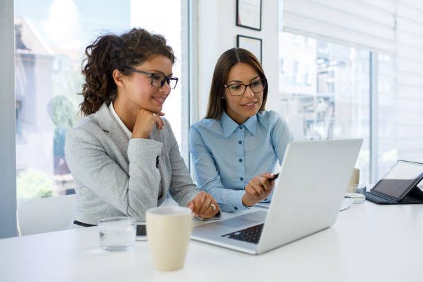 istock Businesswomen with laptop cooperating at work 1163529621