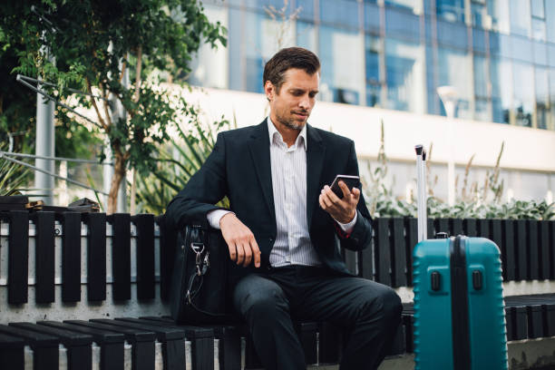 istock Young man using phone on business travel 1163532388