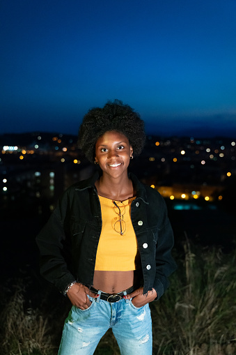 Cool young girl in casual clothes with city lights at background