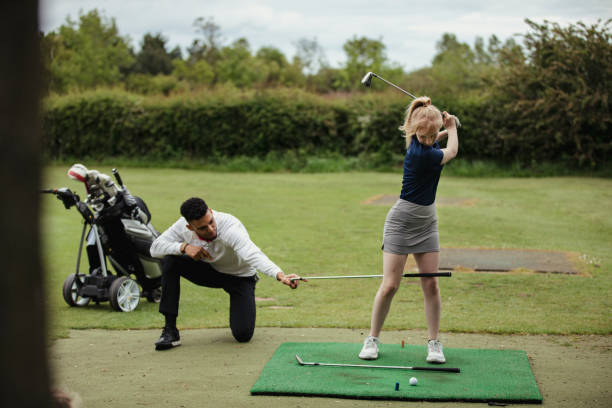 Golf Pro Teaching Teen Girl A front-view shot of a golfing instructor teaching a teenage girl, practicing her swing. golf concentration stock pictures, royalty-free photos & images