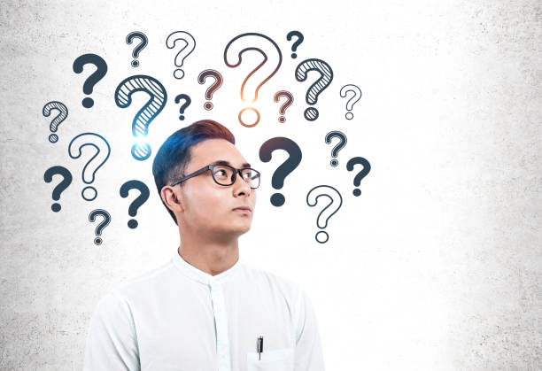 istock Serious Asian man in glasses, question marks 1163534695