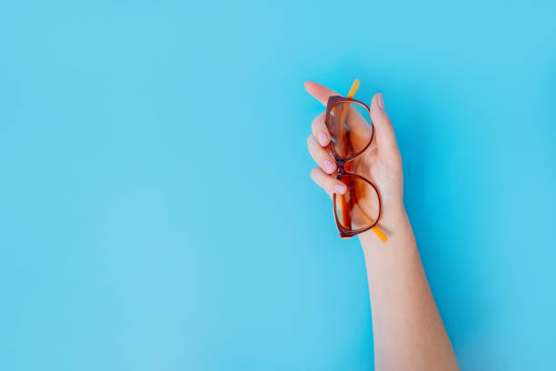 istock Female hand holds glasses on blue background. 1163537386