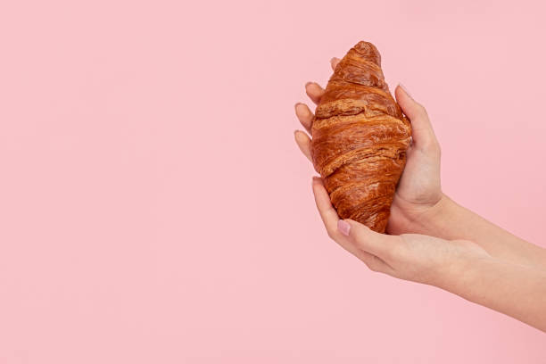 istock Crop hands holding fresh croissant 1163537620