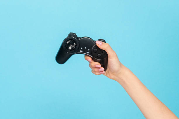 istock Girl with black gamepad on blue backdrop 1163537640