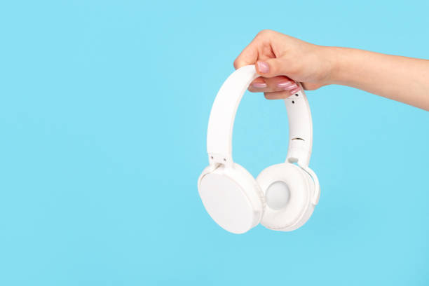 istock Woman advertising wireless earphones on blue backdrop 1163537650