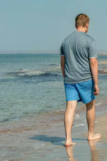 istock Handsome man walking alone on the beach with bare feet. Rest by the beach. 1163538832