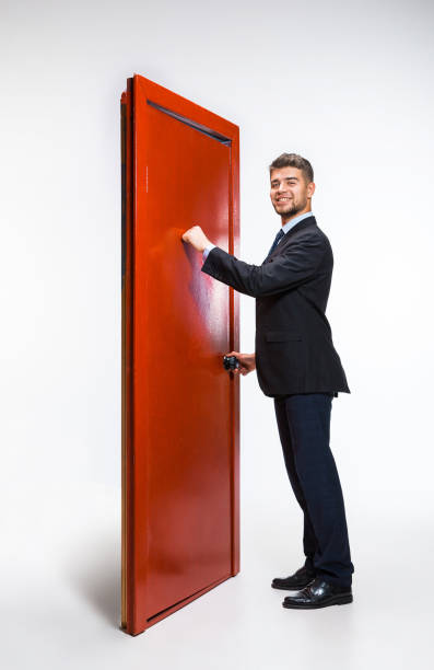 Knocking in emptiness. Young man in black suit trying to open the red door in career ladder, but it's closed. No way for motivation. Concept of office worker's troubles, business, problems, stress.