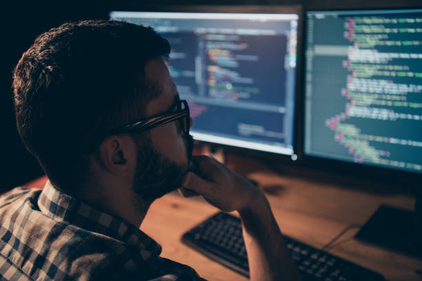 istock Close up back rear behind photo stubble handsome he him his guy support pensive hands arms chin coder code development outsource IT processing two monitors table office wear specs formalwear shirt 1163542121
