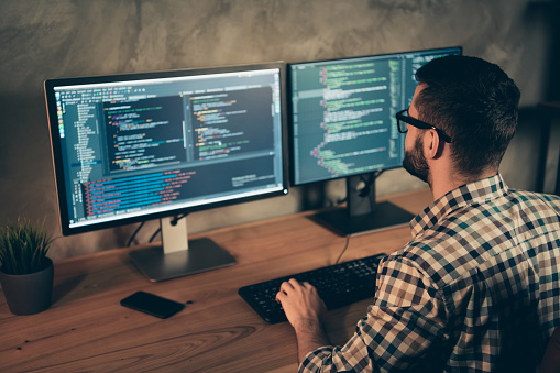 Profile side view of his he nice bearded guy wearing checked shirt professional, expert html data base structure screen at wooden industrial interior work place station