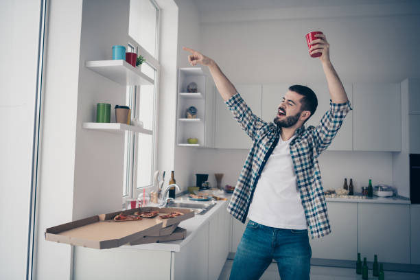 Portrait of his he nice attractive careless carefree cheerful cheery bearded guy wearing checked shirt having fun disco time vacation in modern light white interior style kitchen indoors Portrait of his he nice attractive careless carefree cheerful cheery bearded, guy wearing checked shirt having fun disco time vacation in modern light white interior style kitchen indoors bachelor stock pictures, royalty-free photos & images