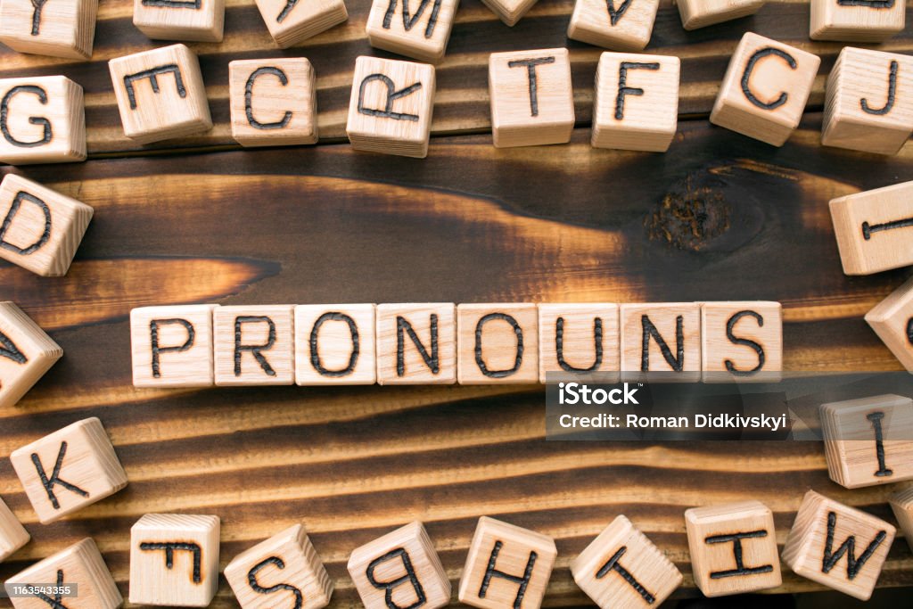word pronouns composed of wooden cubes word pronouns composed of wooden cubes with letters, Part of speech concept scattered around the cubes random letters, top view on wooden background Pronoun Stock Photo