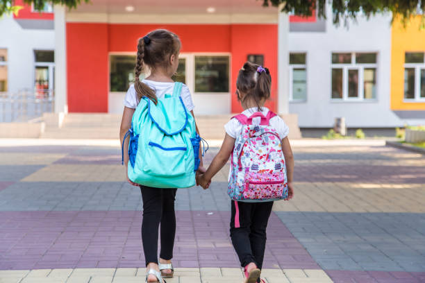 istock Back to school education concept with girl kids, elementary students, carrying backpacks going to class 1163544504
