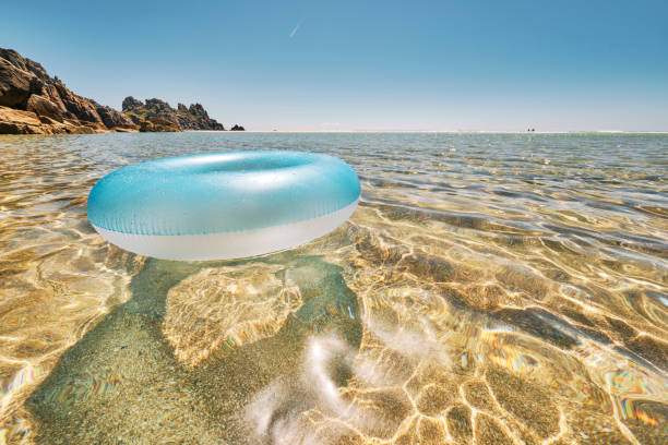 istock Blue rubber ring floating on the clear shallow idyllic sea at Pedn Vounder Beach, Cornwall on a perfect June day. 1163545667