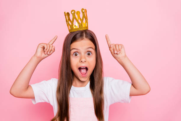 фото маленькая дама праздник время руки указывают головные уборы открытый рот коронации носить солнце платье изолированных розовый фон - women crown tiara princess стоковые фото и изображения