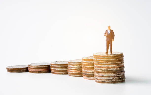 istock Miniature figure business man manager standing on glowing coins stack with white background. Successful investor concept. 1163547328