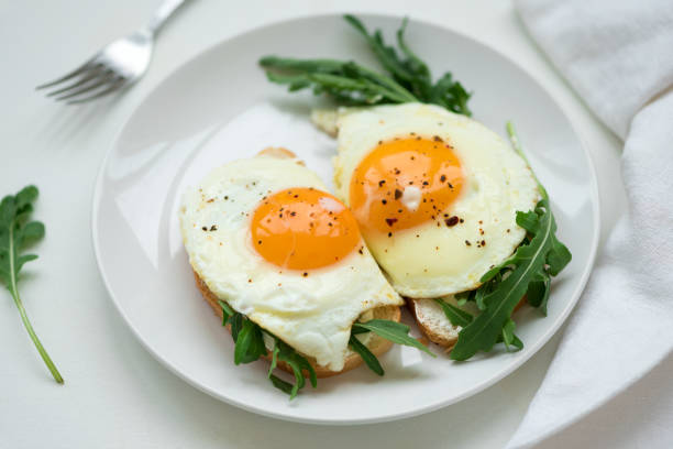 istock Sandwiches with ricotta cheese, arugula and fried egg on white wooden background. Selective focus. Healthy food concept 1163547510