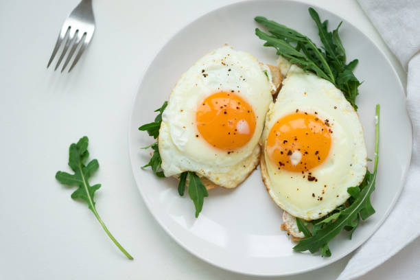 istock Sandwiches with ricotta cheese, arugula and fried egg on white wooden background. Selective focus. Healthy food concept 1163547513
