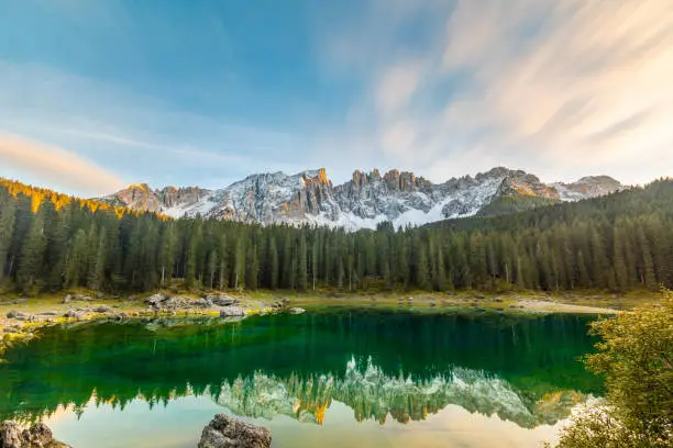 Lake Carezza or Karersee at sunset, wide angle view of scenic landscape in Italy. Dolomites mountains on background, Italian Alps. Nature and travel concepts, long exposure photo