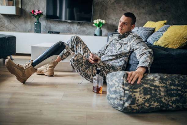 istock Depressed soldier with amputee leg drinking alcohol 1163554932
