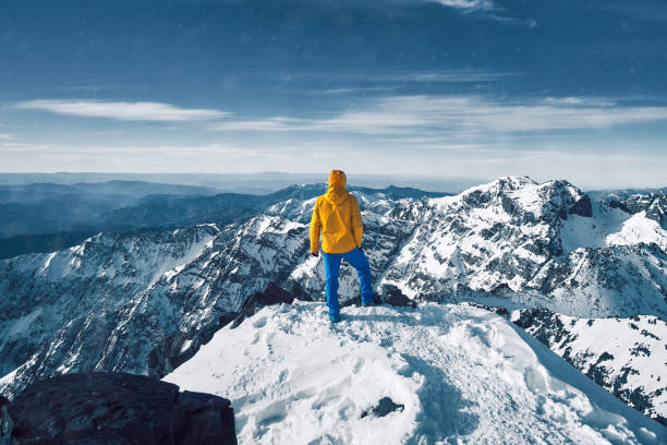 Tourist alone standing and meditating over snow covered Atlas mountain range Alpinist standing at snow covered top of the peak of Jebel Toubkal in Atlas mountains Morocco alpine climate photos stock pictures, royalty-free photos & images