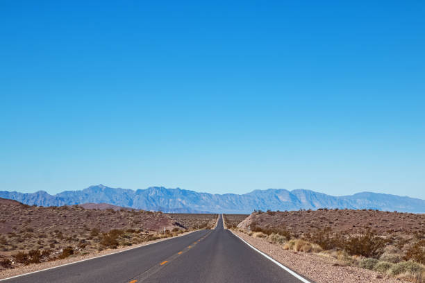 istock Empty asphalt road through the desert in a sunny day with mountains 1163558512