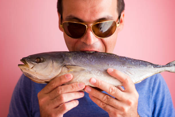 istock Young man with a fish in his hands - salted tuna 1163559465