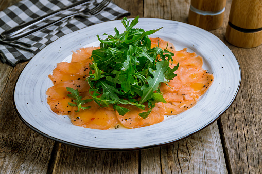 Salmon carpaccio on a plate on wooden table
