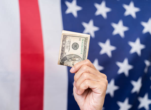 istock Hand holding dollar with America flag background 1163564479