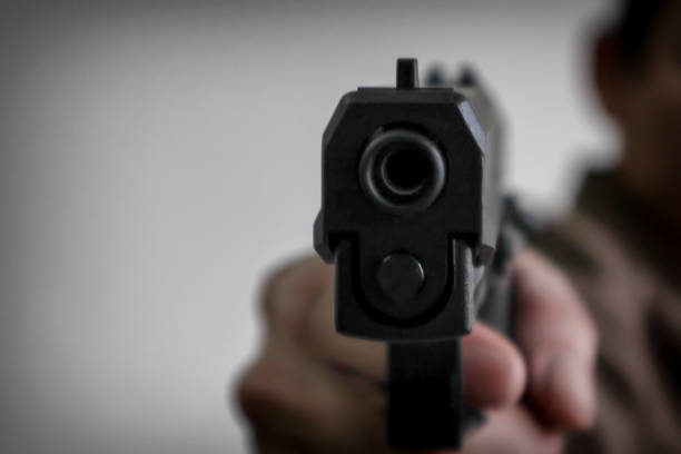 Gunman aiming his target.terrorism shoots a pistrol handgun.Criminal murder and violent concept - Film grain effect stock photo