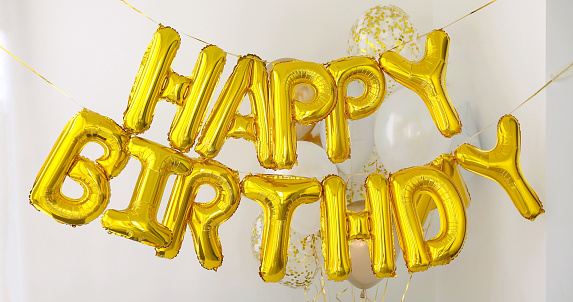 Golden HAPPY BIRTHDAY words made of inflatable balloons on white background