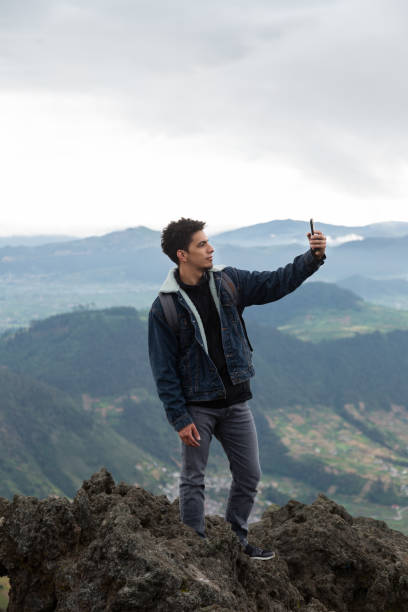 istock Handsome hiker taking a selfie on top of a cliff- man climbing 1163567390